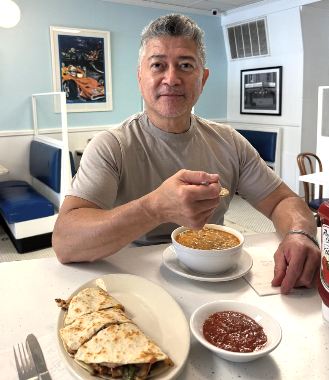 Customer in a booth with a quesadilla, soup, and salsa at Candy Kitchen